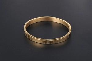 Macro shot of 24K gold plated heart sutra bangle featuring brushed finish and engraving
