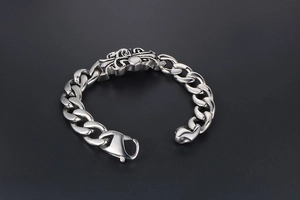 Detail of gothic silver cross plate and chunky Cuban chain on vintage titanium steel bracelet