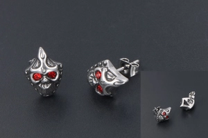 Macro shot of gothic skull stud earrings with red crystal eyes and vintage finish