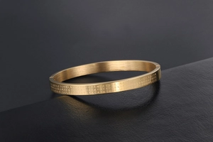 Macro shot of 24K gold plated titanium steel heart sutra bracelet with matte brushed finish