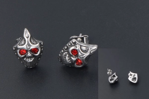 Macro view of vintage skull mask earring with red rhinestones and needle clasp detail