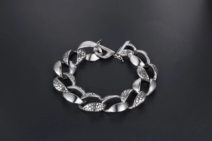 Macro detail of men's silver snake scale link bracelet with a wide rectangular clasp