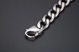 Close-up of polished silver titanium steel Cuban chain bracelet with a large lobster clasp