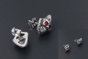 Detailed macro shot of skull stud earring with red gemstone eyes and vintage silver finish