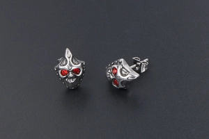 Macro shot of punk skull stud earrings in stainless steel with vibrant red rhinestone eyes