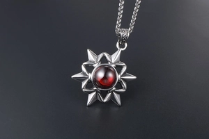 Detailed close-up of a vintage steel star pendant with a red gemstone on a chain