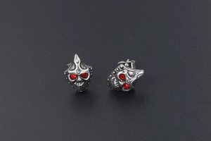 Macro detail of gothic skull stud earrings with red crystal eyes in vintage steel