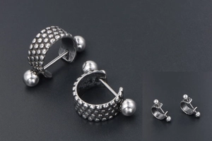Detail of punk style titanium steel earrings with dotted texture and antique silver finish