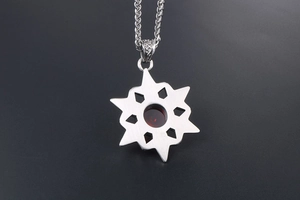 Macro view showing the brushed metal back of a silver star pendant with a red stone