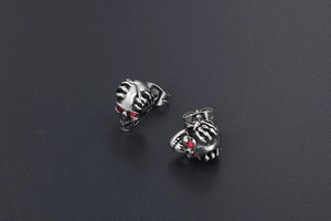 Gros plan de boucles d'oreilles crâne gothiques en argent vieilli avec yeux rouges