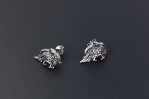 Detailed view of silver lion head earrings with sparkling red gemstone eyes