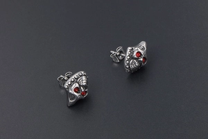 Detailed view of silver skull earrings with red crystal eyes in gothic punk style