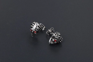 Détail macro de boucles d'oreilles crâne avec yeux en cristal rouge et fini argent