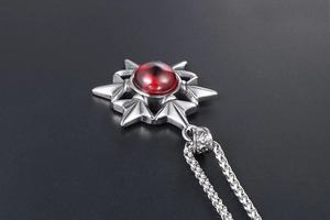 Close-up of gothic star pendant with red gemstone and thick metal chain link