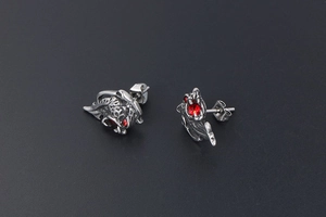 Detailed macro view of silver lion head earrings featuring sparkling red gemstone eyes