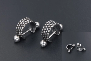 Macro detail of silver punk C-shaped earrings with textured dots and ball ends