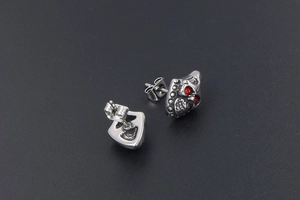 Macro view of vintage titanium steel skull stud earrings with red cubic zirconia eyes
