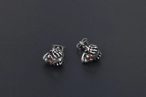 Détail macro de boucles d'oreilles crâne avec yeux rouges et fini argenté vieilli
