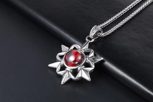 Detail of vintage silver star pendant with large red gemstone on black leather background