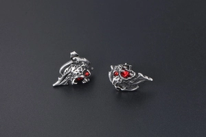 Detail of silver lion head stud earrings with red crystal eyes and polished steel finish