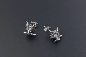 Detailed close-up of punk style wolf head stud earrings with sword in mouth design