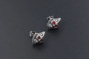Detail of vintage skull stud earrings with red crystal eyes and polished finish