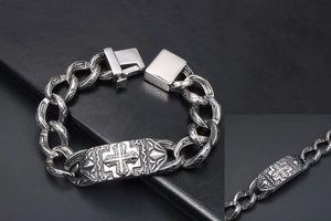 Dettaglio di incisione a croce gotica su un bracciale in metallo a catena larga da uomo