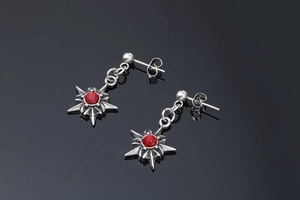 Détail de boucles d'oreilles étoile en argent avec rubis rouge de style punk gothique