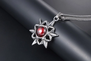 Macro shot of silver hexagram star pendant featuring a vibrant red gemstone center