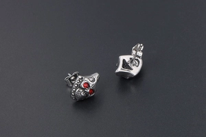Macro detail of gothic skull stud earrings with red crystal eyes and metal butterfly back