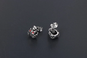 Gros plan sur boucles d'oreilles tête de mort en acier avec yeux en cristal rouge vif