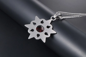 Macro detail of silver star pendant with red gemstone and brushed metal texture