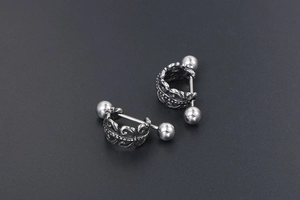 Gros plan détaillé de boucles d'oreilles barbell en acier avec gravure filigrane