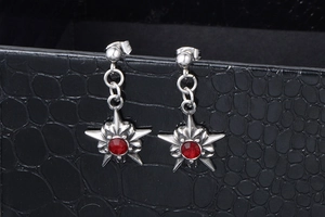 Vue macro de boucles d'oreilles punk en forme d'étoile argentées avec strass rouge central