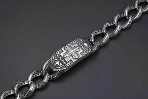 Dettaglio macro dell'incisione a croce gotica su bracciale a catena d'argento vintage da uomo