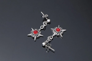 Gros plan de boucles d'oreilles punk en forme d'étoile avec pierre rouge sur fond noir