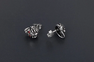 Détail macro de boucles d'oreilles tête de mort avec yeux rouges et fini argenté vintage