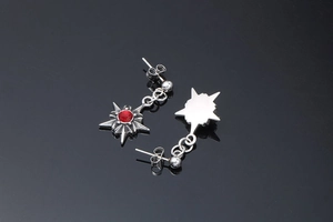 Détail de boucles d'oreilles punk en forme d'étoile avec pierre rouge sur fond noir