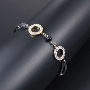 Titanium steel bracelet with gold and rose gold rhinestone rings and a black bead
