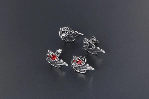Macro detail of lion-head stud earrings with red and black gems in retro punk style
