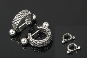 Macro detail of silver titanium steel earrings with punk woven chain texture and polished finish