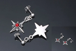Dettaglio macro degli orecchini a stella in acciaio al titanio con zircone rosso brillante