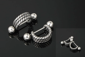 Close-up of punk style twisted steel hoop earrings with ball ends on black surface