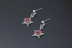 Macro d'oreilles punk en forme d'étoile avec rubis rouge sur un miroir gris