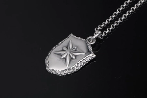 Macro d'un pendentif bouclier argenté avec étoile polaire et texture martelée sur fond noir