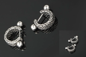 Macro detail of silver titanium steel C-hoop earrings with braided texture and screw ball