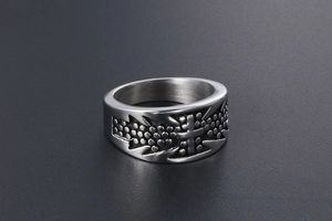 Close-up of titanium steel cross ring with textured dots and serrated punk style edges