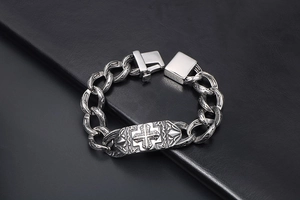 Dettaglio della placca con croce vintage su un bracciale a catena cubana pesante