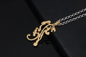 Close-up of golden dragon pendant with intricate hollow design on silver chain necklace