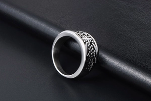 Macro shot of silver titanium steel cross ring with embossed black dotted patterns